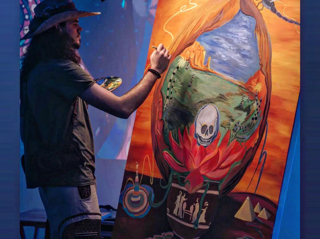 A painter working live on a large surrealist canvas at a Lemonade Arts gathering.